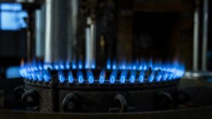 калькулятор расхода газа на отопление — синее пламя горелки газового котла крупным планом в тёмной котельной